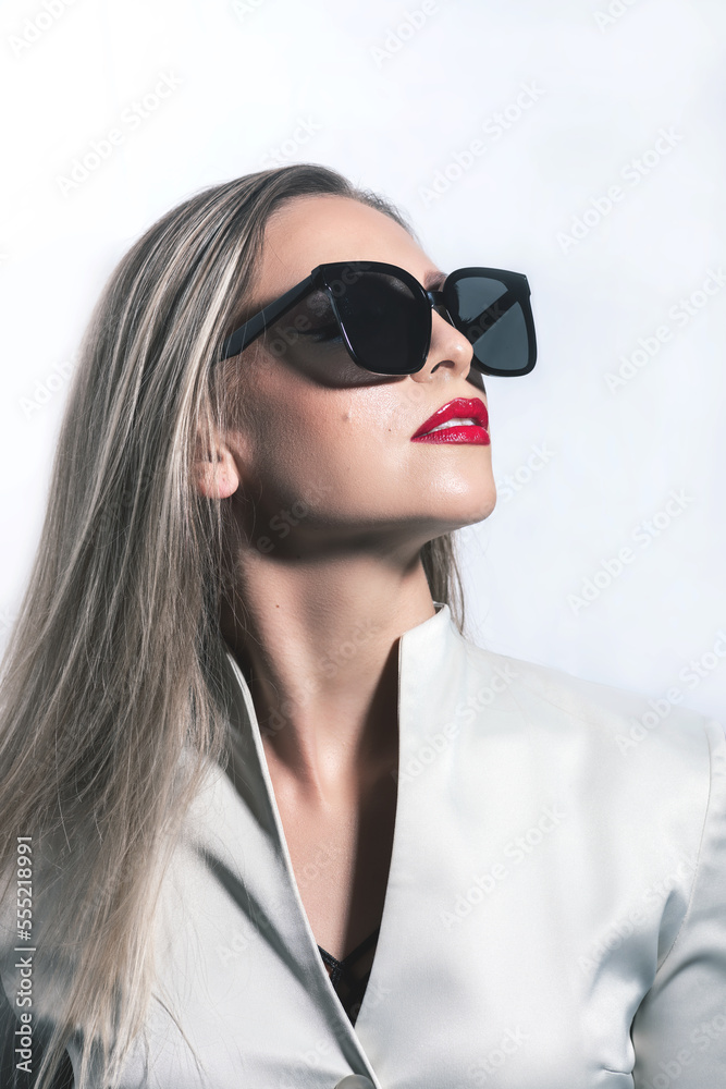 Fashion, make-up and lifestyle concept. Beautiful woman close-up studio portrait with sunglasses and red lips looking aside the camera with serious look. Toned image with soft gray color Fashion, make-up and lifestyle concept. Beautiful woman close-up studio portrait with sunglasses and red lips looking aside the camera with serious look. Toned image with soft gray color
