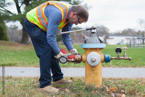 Technician installing hydrant attachment with sensor for flushing mains photo