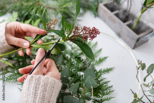 The process of making a Christmas wreath from needles, thuja, shimia, rosehip, pine twigs, chopped twigs for the wreath. The concept of preparation for Christmas and New Year. photo