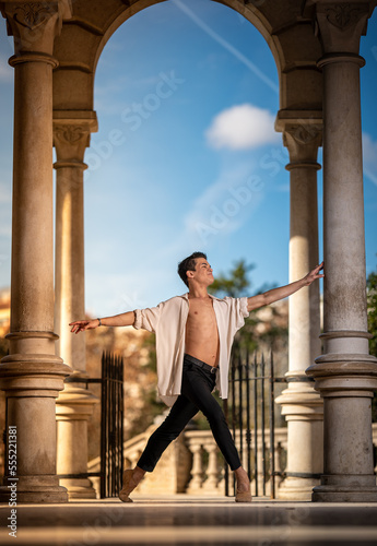 Young man dancing classic ballet in the streets of Barcelona with a beautiful background and light