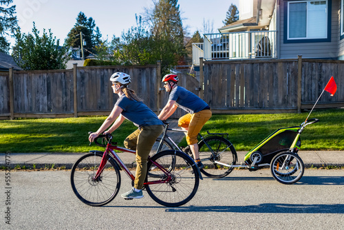 Family biking together during COVID-19, staying carefully apart from the photographer, during days of isolation; North Vancouver, British Columbia, Canada photo