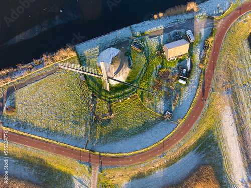 Strijkmolen E, Ouddorp, Alkmaar, North Holland,The Netherlands. Oak octagonal polder mill from 1630. Ironing mills do not drain polders, grind the water from one reservoir to the other. Winter aerial. photo