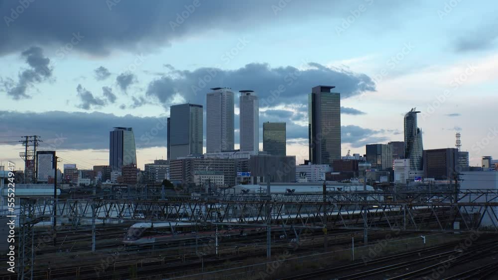 NAGOYA, JAPAN - OCT 2022 : View of buildings around NAGOYA STATION and railroad in sunset from Koyabashi (bridge). Time lapse shot, dusk to night. Japanese business and transportation concept video. NAGOYA, JAPAN - OCT 2022 : View of buildings around NAGOYA STATION and railroad in sunset from Koyabashi (bridge). Time lapse shot, dusk to night. Japanese business and transportation concept video.