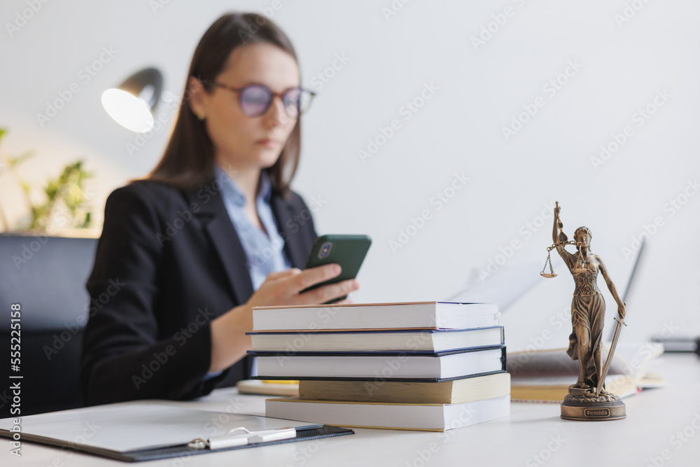 female lawyer in strict suit works in office or court, checks clients' contracts, chats by phone. Caucasian successful business lady, statuette of Themis, goddess of justice. legal advice online. female lawyer in strict suit works in office or court, checks clients' contracts, chats by phone. Caucasian successful business lady, statuette of Themis, goddess of justice. legal advice online.