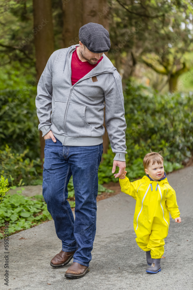 Father holding hands with young daughter while taking a walk in the park; North Vancouver, British Columbia, Canada Father holding hands with young daughter while taking a walk in the park; North Vancouver, British Columbia, Canada