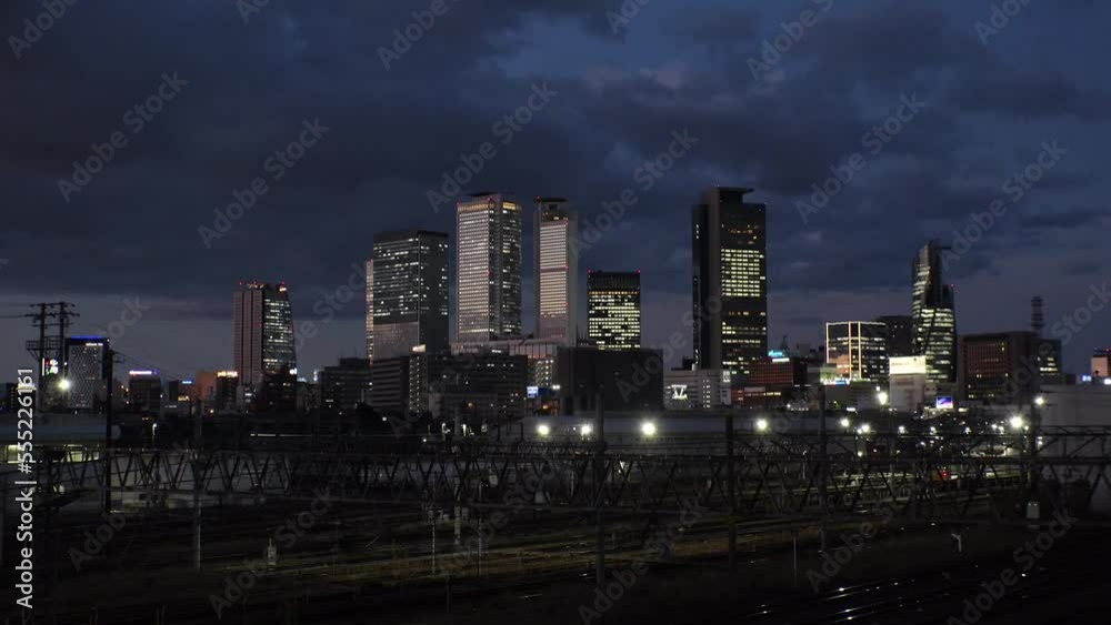 NAGOYA, JAPAN - OCT 2022 : View of buildings around NAGOYA STATION and railroad in sunset from Koyabashi (bridge). Time lapse shot, dusk to night. Japanese business and transportation concept video.