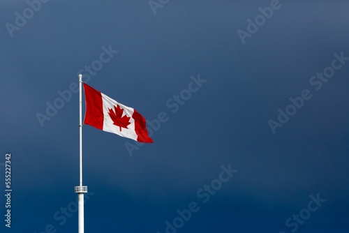 Canadian flag on a white flag pole flying in a blue sky; Surrey, British Columbia, Canada photo
