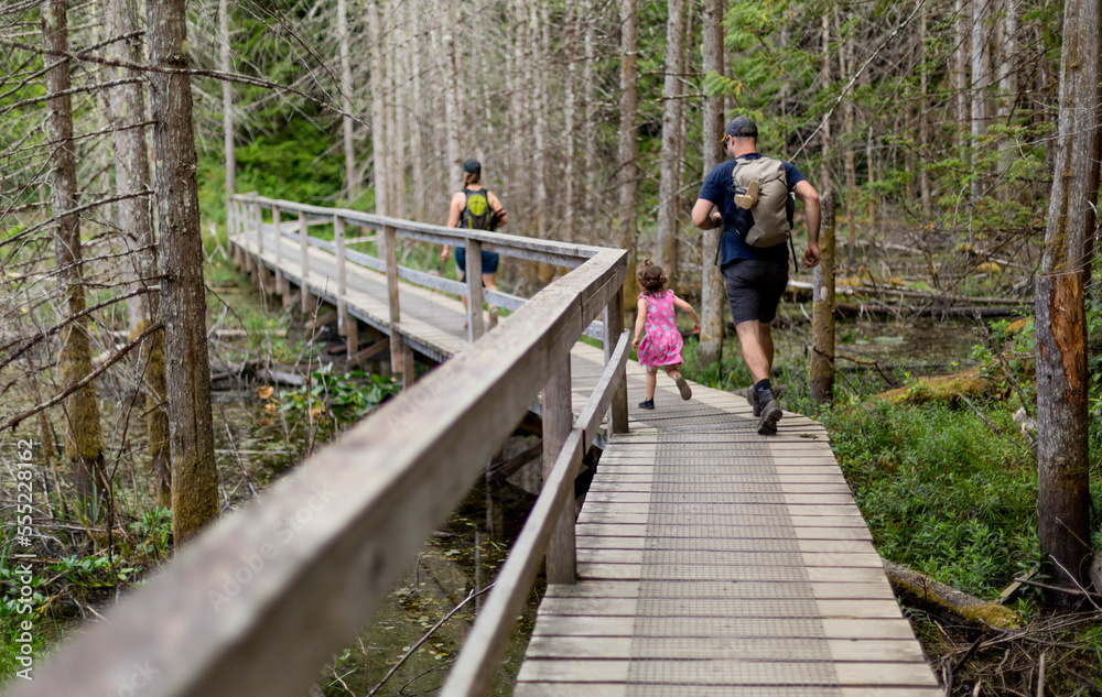 Young family hiking on a boardwalk trail together in Smuggler Cove Marine Provincial Park along the Sunshine Coast of BC, Canada; British Columbia, Canada Young family hiking on a boardwalk trail together in Smuggler Cove Marine Provincial Park along the Sunshine Coast of BC, Canada; British Columbia, Canada