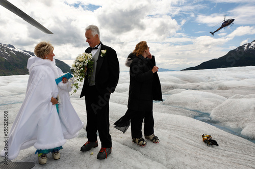 A newly married couple waits to fly by helicopter to a cruise ship, Mendenhall Glacier, Alaska, USA photo