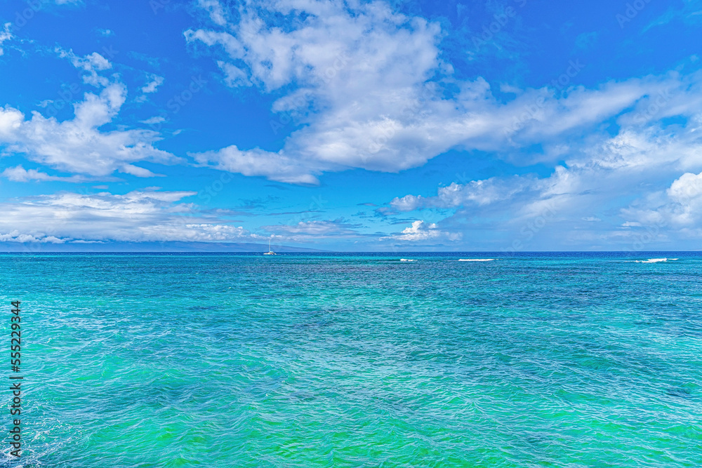 View of the turquoise water of the Pacific Ocean with a pleasure boat moored off shore along the horizon on a beautiful, sunny day in Lahaina; Maui, Hawaii, United States of America View of the turquoise water of the Pacific Ocean with a pleasure boat moored off shore along the horizon on a beautiful, sunny day in Lahaina; Maui, Hawaii, United States of America
