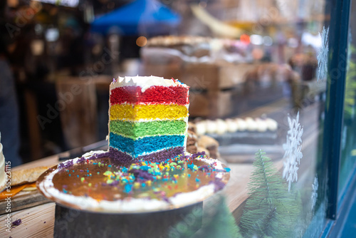 A piece of cake with layers in the order of the colors of the rainbow on display for sale