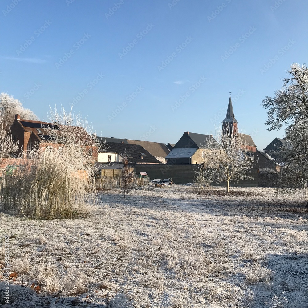 Pâturage couvert de givre sous un ciel clair d'hiver derrière les fermes à Ghislenghien Pâturage couvert de givre sous un ciel clair d'hiver derrière les fermes à Ghislenghien