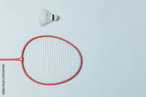 Single badminton racket and shuttlecock isolated on light blue colored background for psychology or lifestyle blog, women sports, solitude, melancholy, loneliness.