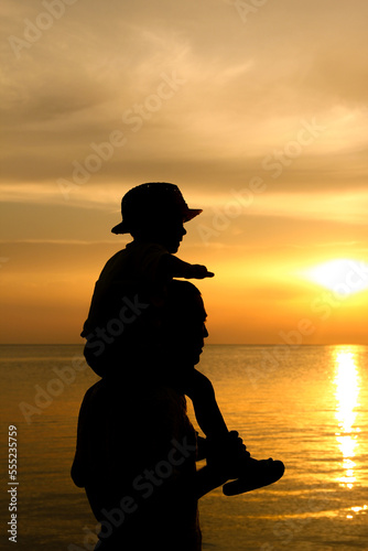A happy parent with child by the sea in nature on a trip silhouette © Kostia