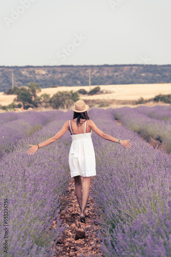 Fototapeta Naklejka Na Ścianę i Meble -  woman in white dress walking through a lavender field