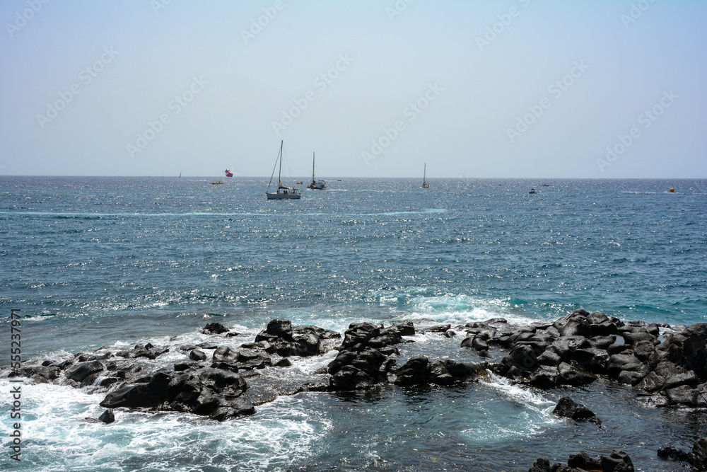 Hustle and bustle on the sea with many boats, rocks in the foreground