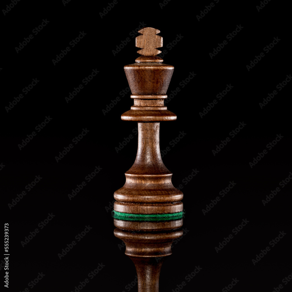 Wooden black chess king isolated at dark background Wooden black chess king isolated at dark background