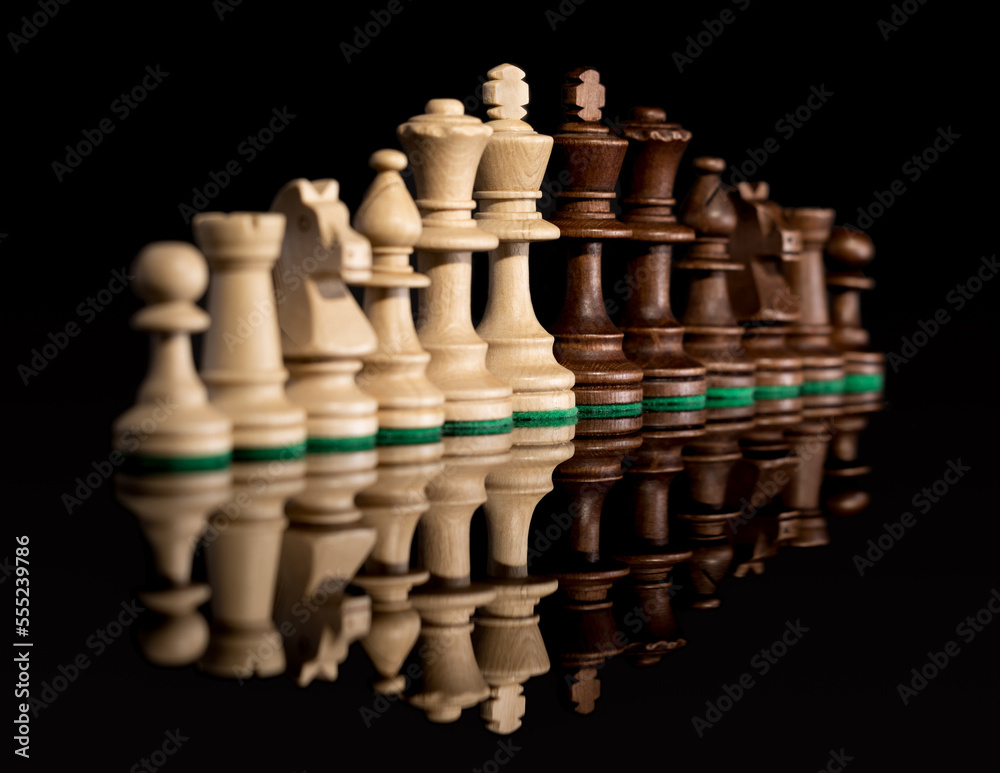 Diagonal line of wooden chess pieces isolated at dark background Diagonal line of wooden chess pieces isolated at dark background