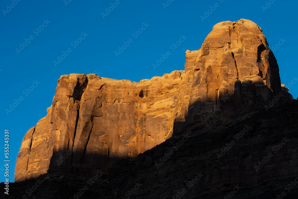 Sun setting on red sandstone canyon wall in Canyonlands, Utah