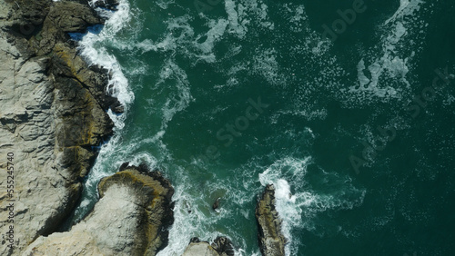 Top down aerial of emerald ocean water and rocky cliffs near San Francisco, California