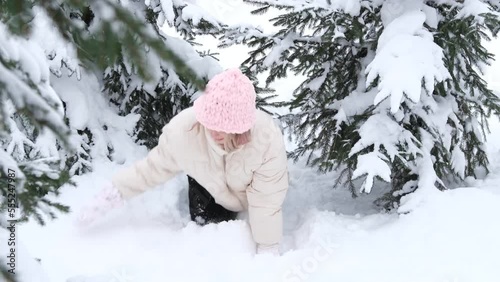 Happy winter time. Well dressed woman wriggle between fir trees and play with snow thow it up enjoying the winter. photo