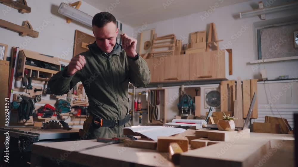 A carpenter is dancing in the workshop. Dance of the Happy Carpentry Worker