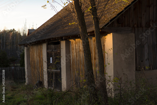 Stara stodoła murowana i z drewna , o dachu pokrytym betonowymi ( cementowymi ) dachówkami . Jesień - zachód słońca . photo