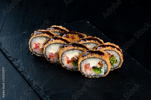 Japanese tempura sushi rolls with shrimp, sea bass, lettuce, cream cheese, sweet pepper and teriyaki sauce.