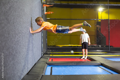 Expressive cheerful tween boy enjoying jumping on trampoline on indoor inflatable playground..