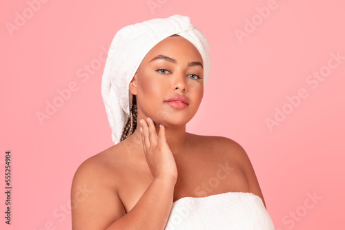 Attractive african american plus size woman touching her face, enjoying silky touch after using nourishing cream