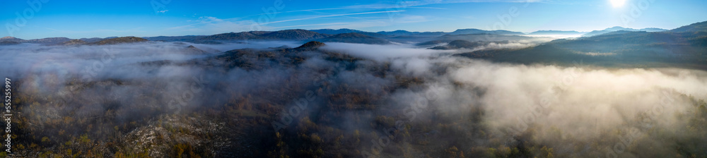 Aerial view around foggy mountain top in Montenegro on an early sunny morning in autumn.