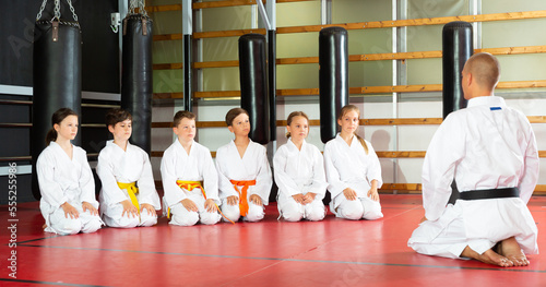 Group of positive preteen children greeting karate coach at sport gym