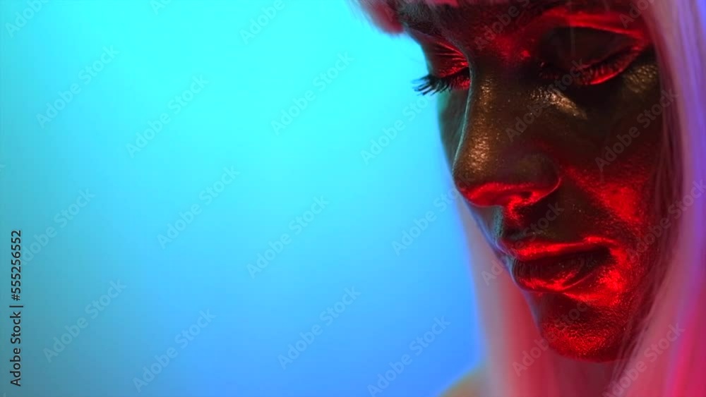 Glowing gold skin. Fashion model woman face in bright neon colourful lights, beautiful sexy woman with white hair and trendy make-up. Art design make up. Glittering, golden, metallic shine makeup. Glowing gold skin. Fashion model woman face in bright neon colourful lights, beautiful sexy woman with white hair and trendy make-up. Art design make up. Glittering, golden, metallic shine makeup.