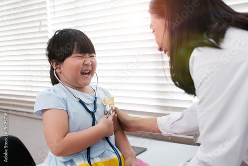 Asian doctor diagnosing on young girl patient   smiling happy getting tested concept  checking her heartbeat with stethoscope  in hospital clinical office room  diagnosis for illness disease sickness