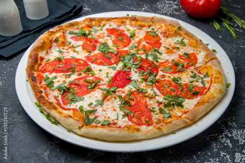 Italian pizza Margherita with cheese. and tomatoes on dark table