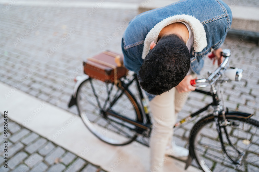 Obraz premium Young man in denim jacket looking at what is happening on his vintage classic bike.
