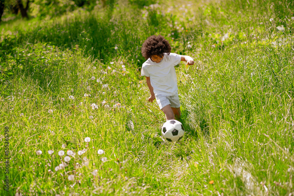 Curly-haired boy in white sportswear playing football Curly-haired boy in white sportswear playing football