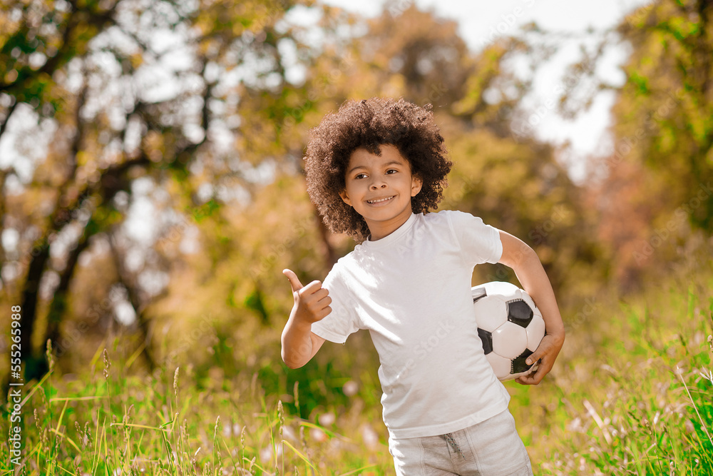 Curly-haired boy in white sportswear with a football Curly-haired boy in white sportswear with a football