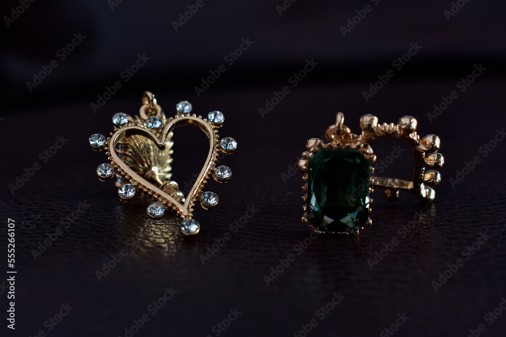Gold earrings decorated with green gems. that shines beautifully Gold earrings decorated with green gems. that shines beautifully