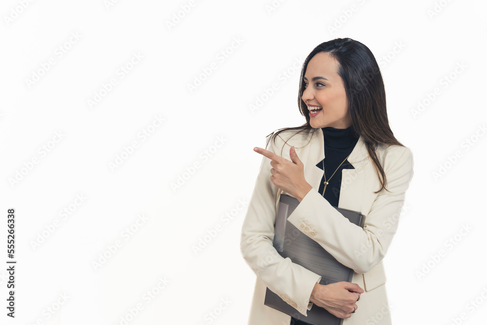Latin american modern businesswoman looking to the side smiling holding document folder and pointing to empty space on the left with one hand. White background horizontal studio shot. High quality Latin american modern businesswoman looking to the side smiling holding document folder and pointing to empty space on the left with one hand. White background horizontal studio shot. High quality