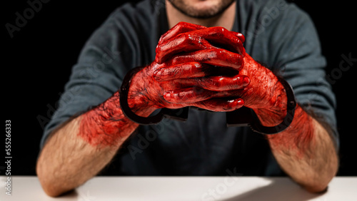 Portrait of a man with bloody hands handcuffed.