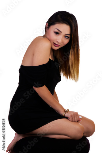 Attractive Asian American Woman Kneeling In Black Dress On White