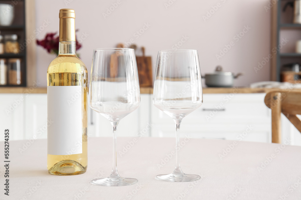 Bottle of wine and empty glasses on dining table in kitchen