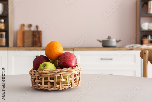 Fototapeta Naklejka Na Ścianę i Meble -  Wicker basket with delicious fruits on dining table in kitchen