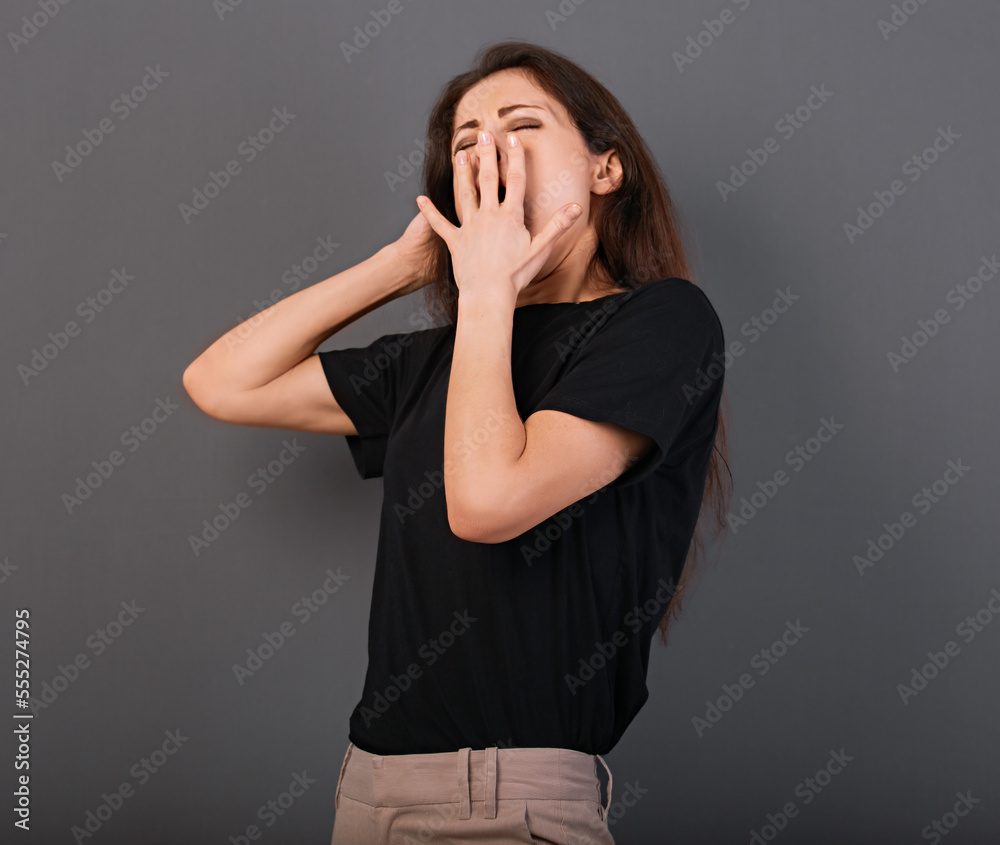Beautiful business tired woman want to sleep and yawning covering the hand the mouth in black shirt on grey background with empty copy space. Closeup Beautiful business tired woman want to sleep and yawning covering the hand the mouth in black shirt on grey background with empty copy space. Closeup