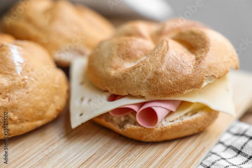 Kaiser rolls with ham and cheese on wooden board photo