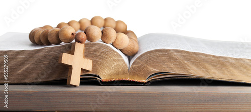 Rosary beads on open bible on wooden table