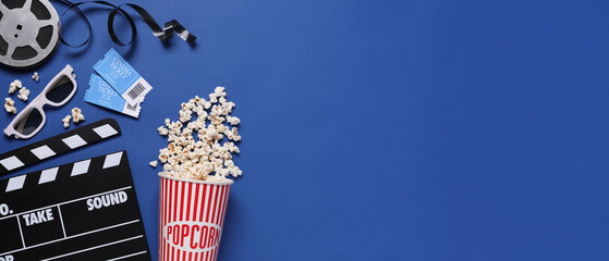 Flat lay composition with clapperboard, cinema tickets and popcorn on blue background, space for text. Banner design