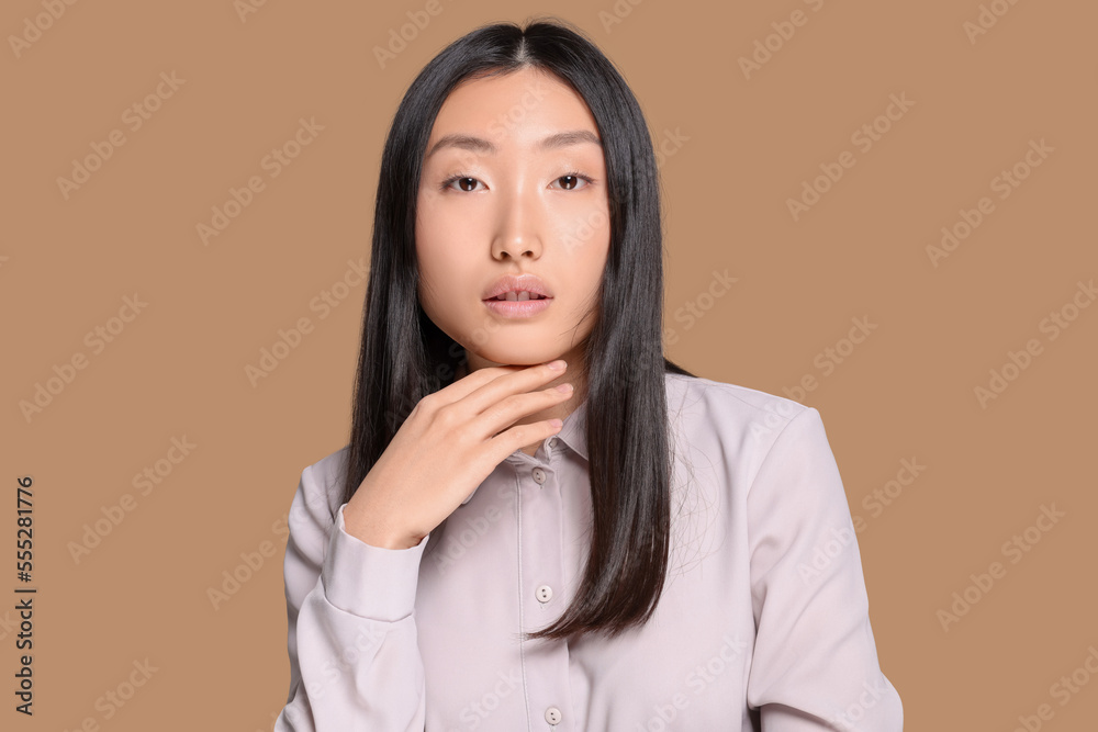 Portrait of beautiful young Asian woman in stylish outfit on beige background Portrait of beautiful young Asian woman in stylish outfit on beige background