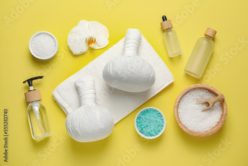 Beautiful spa composition with herbal massage bags and different care products on yellow background, flat lay